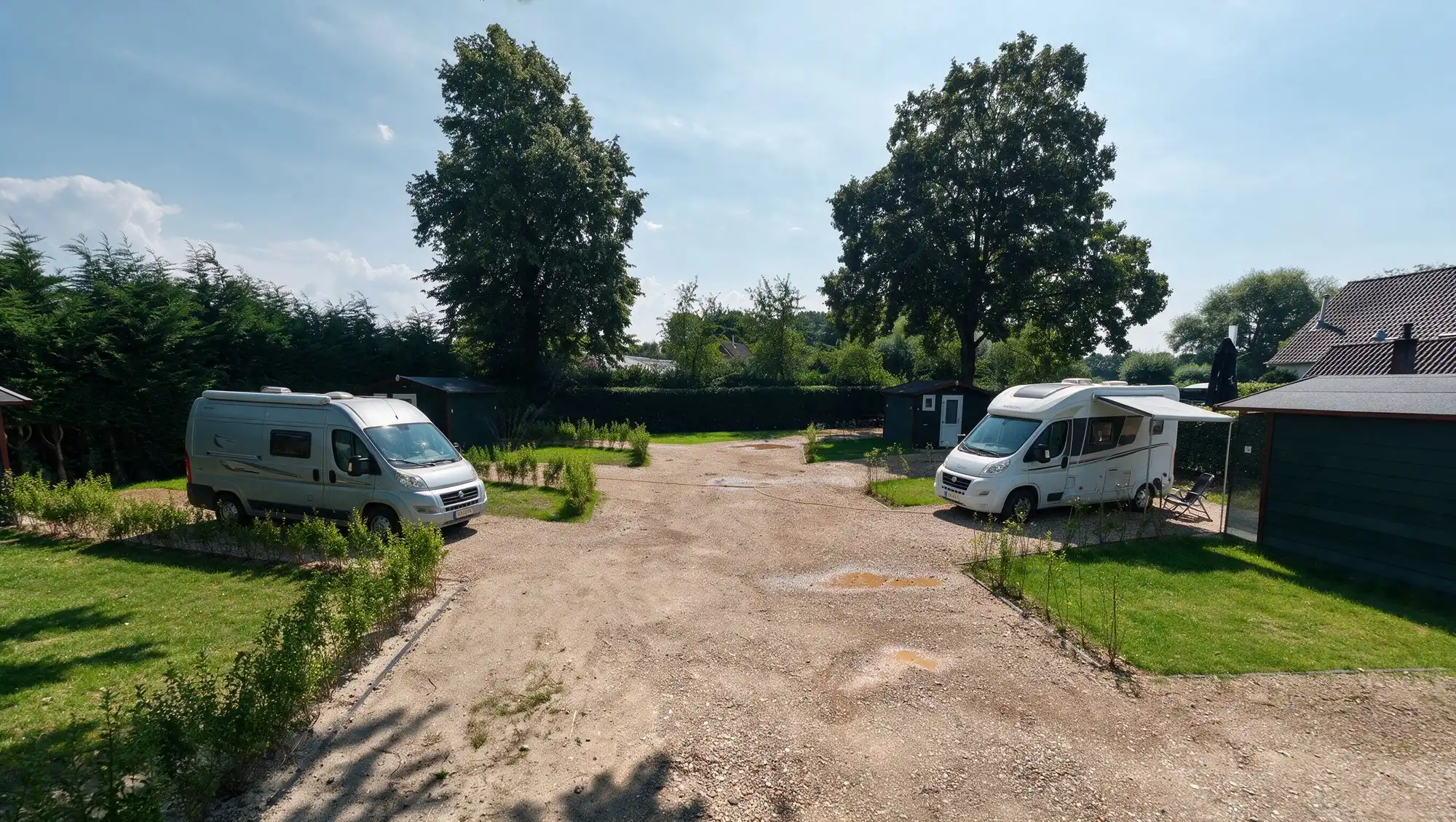 Twee campers op de camperplaatsen van Resort de Betuwe, elk met een eigen sanitairunit naast de plek