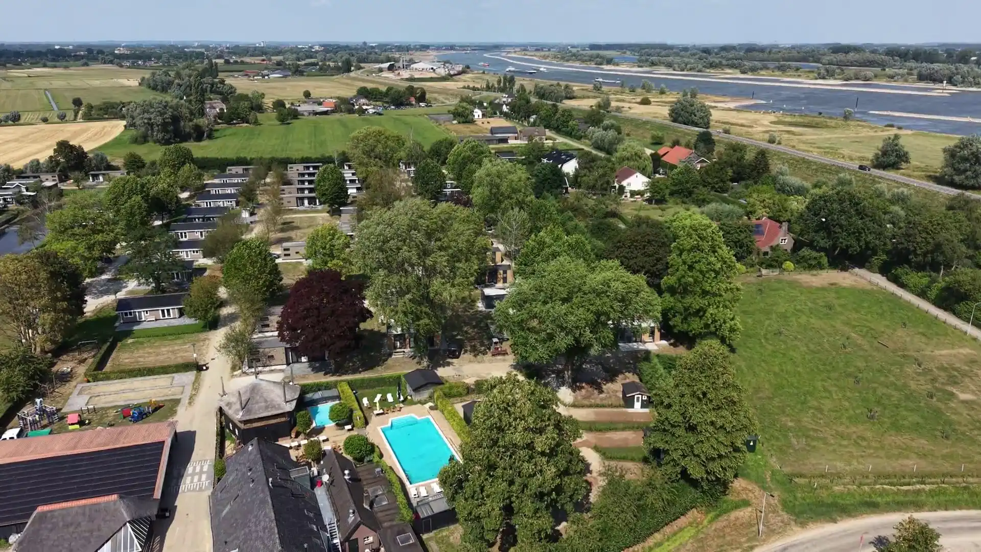 Het terrein van Resort de Betuwe met water en groen tussen de vakantiehuisjes